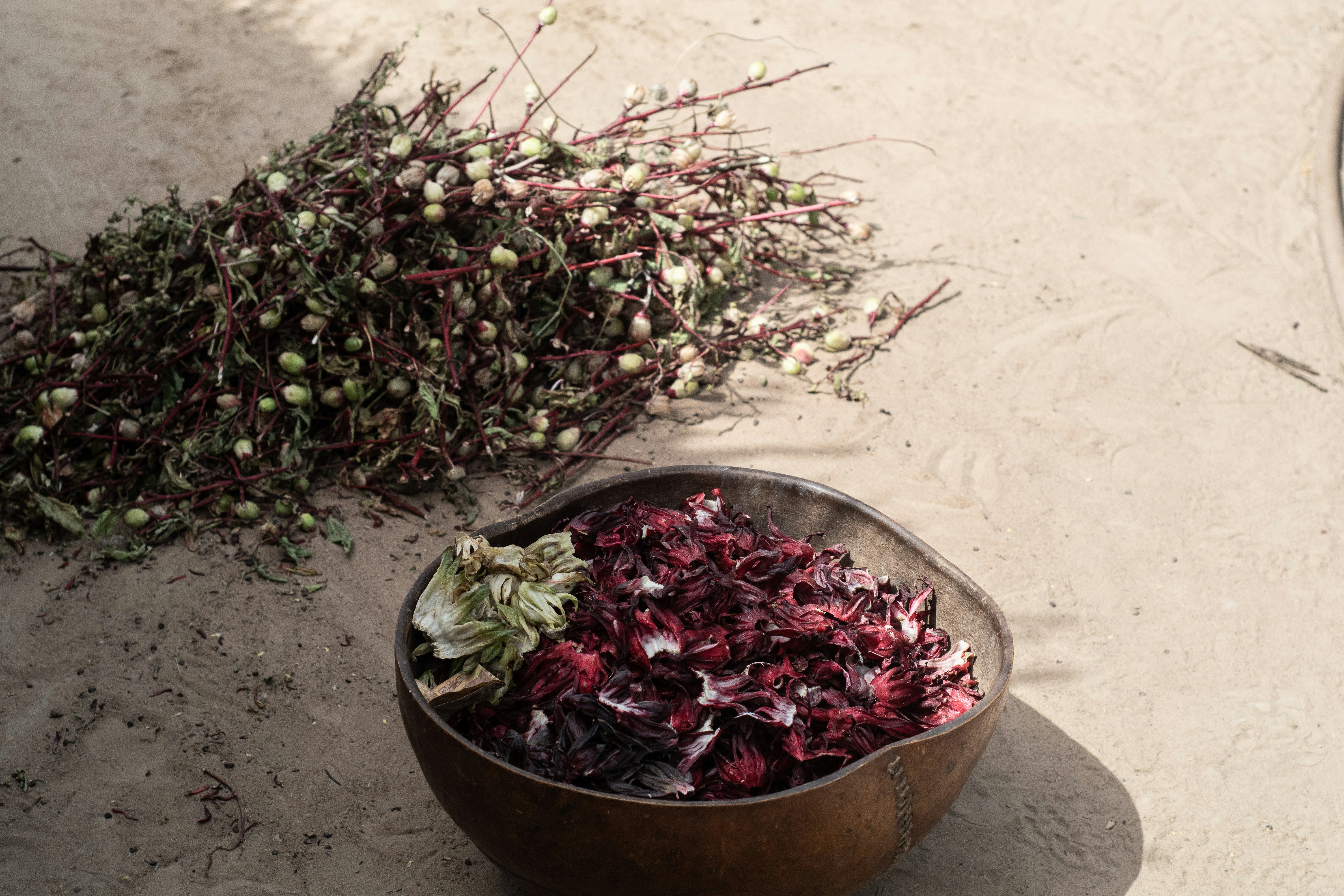 a bucket of dried flowers sitting next to a pile of dried flowers, Awesome bissap.