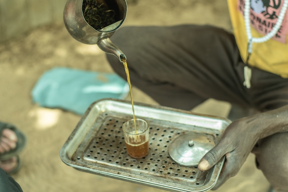 a person pouring something into a glass on a tray