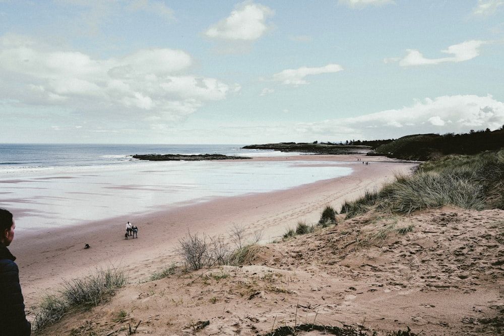 a man standing on top of a sandy beach next to the ocean