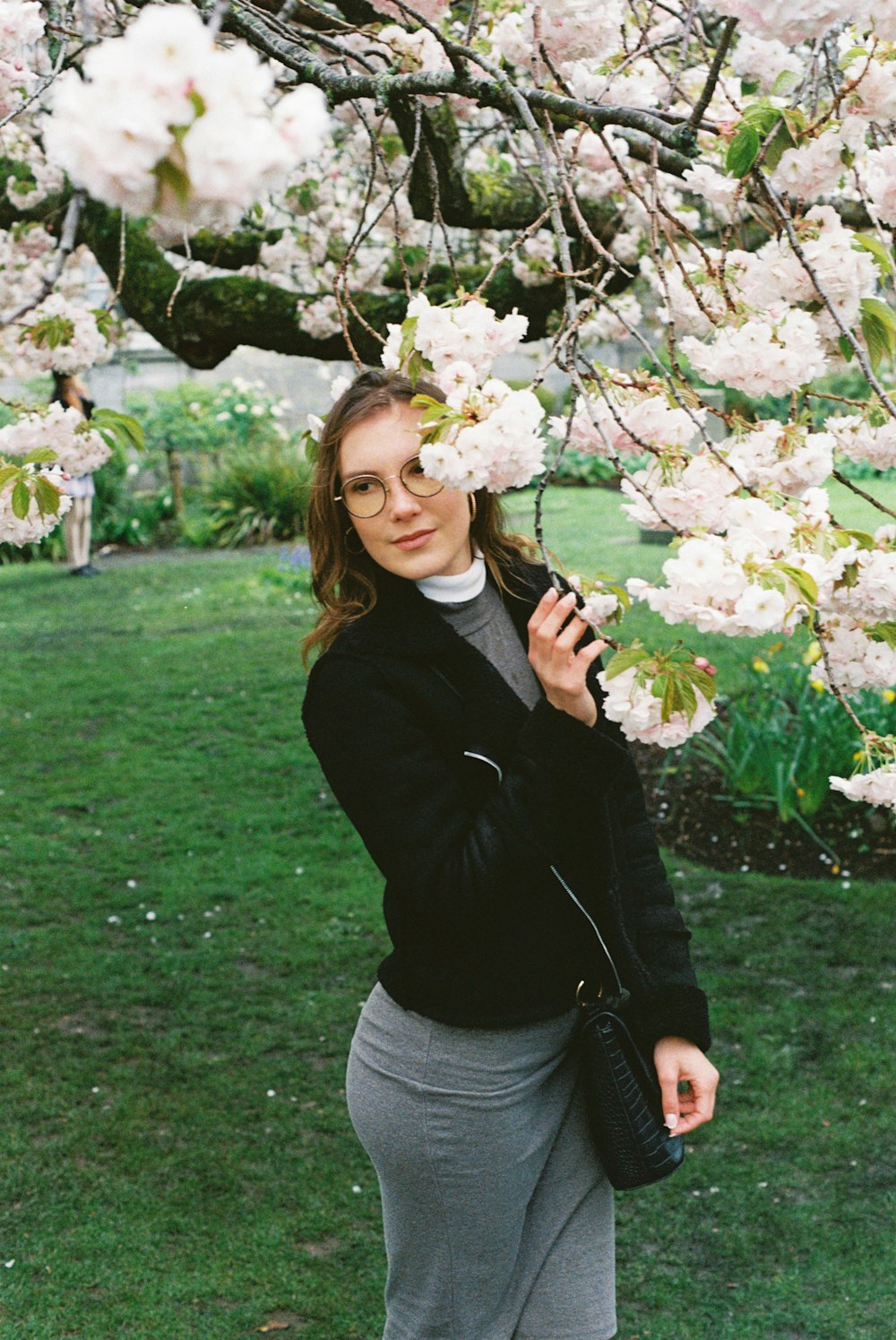 a woman is standing under a flowering tree