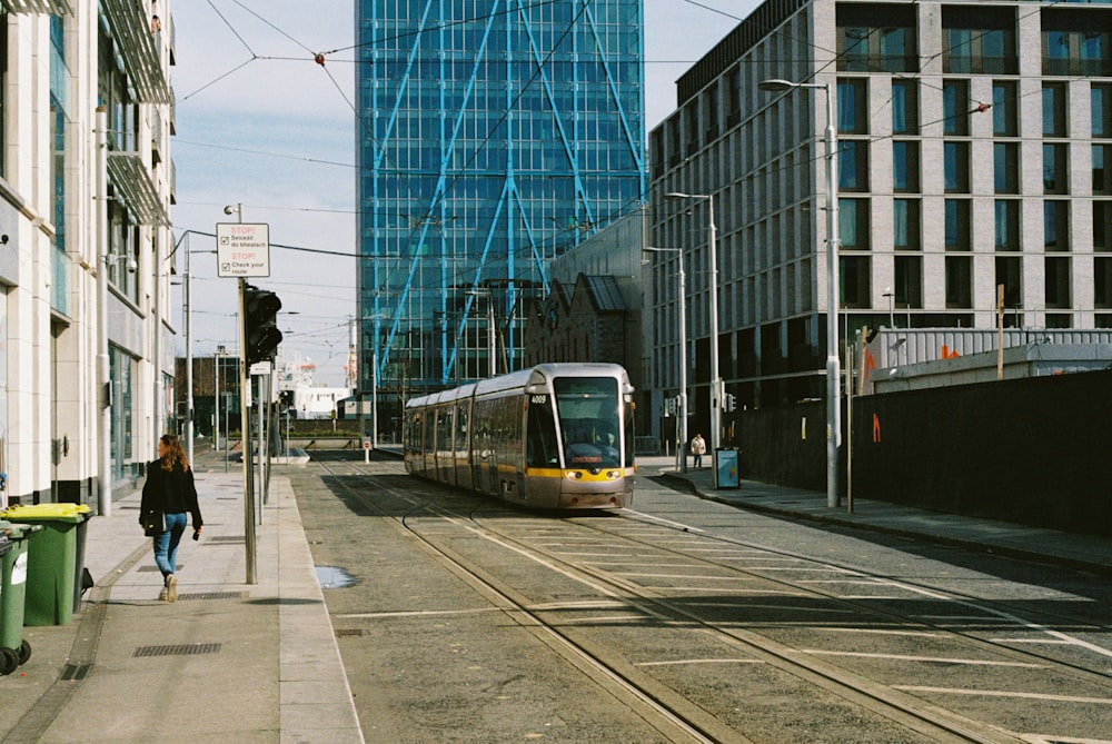 a person walking on a sidewalk next to a train