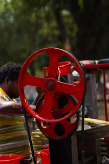 a man working on a machine with a red wheel