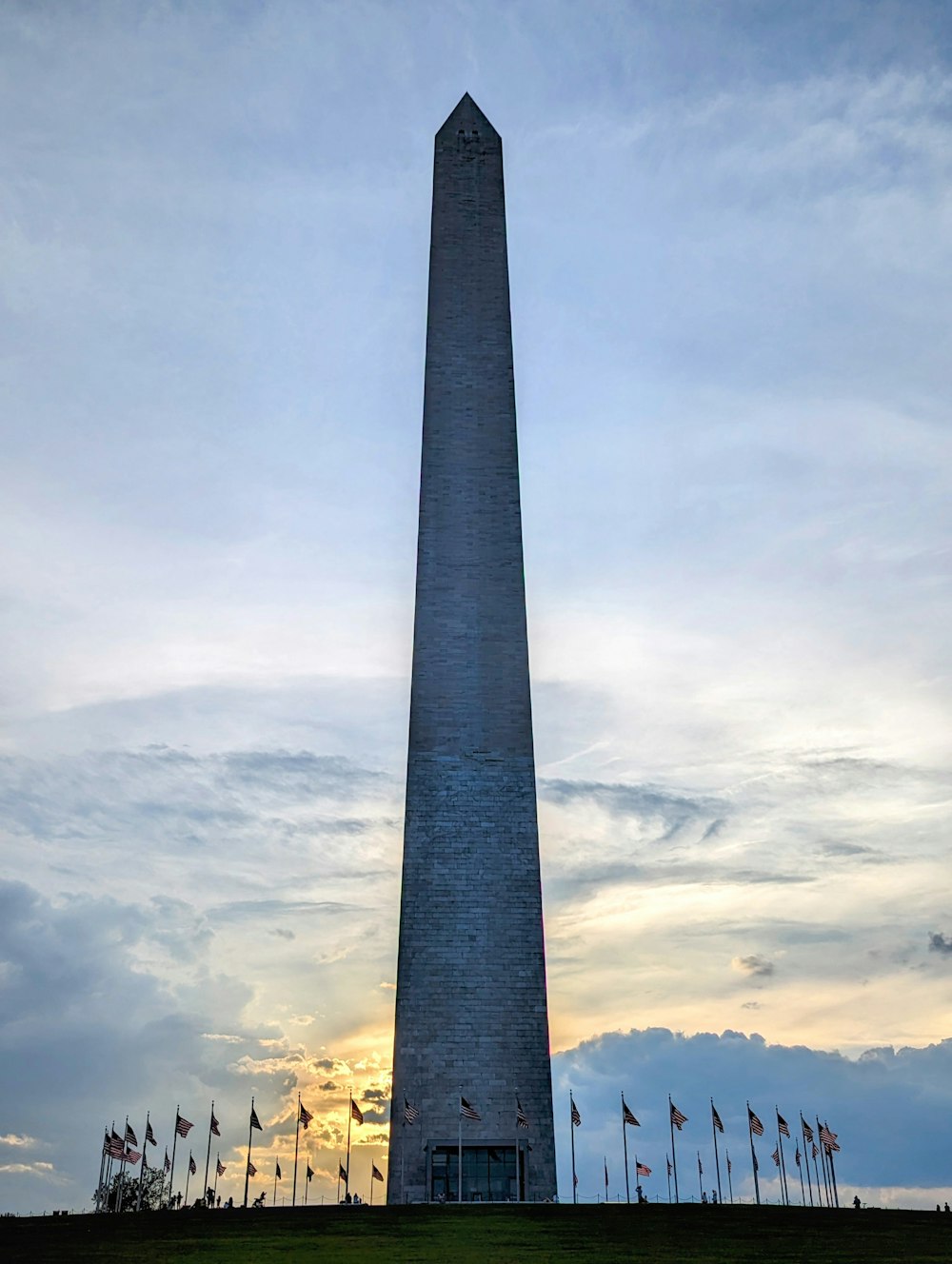 the washington monument is silhouetted against a cloudy sky