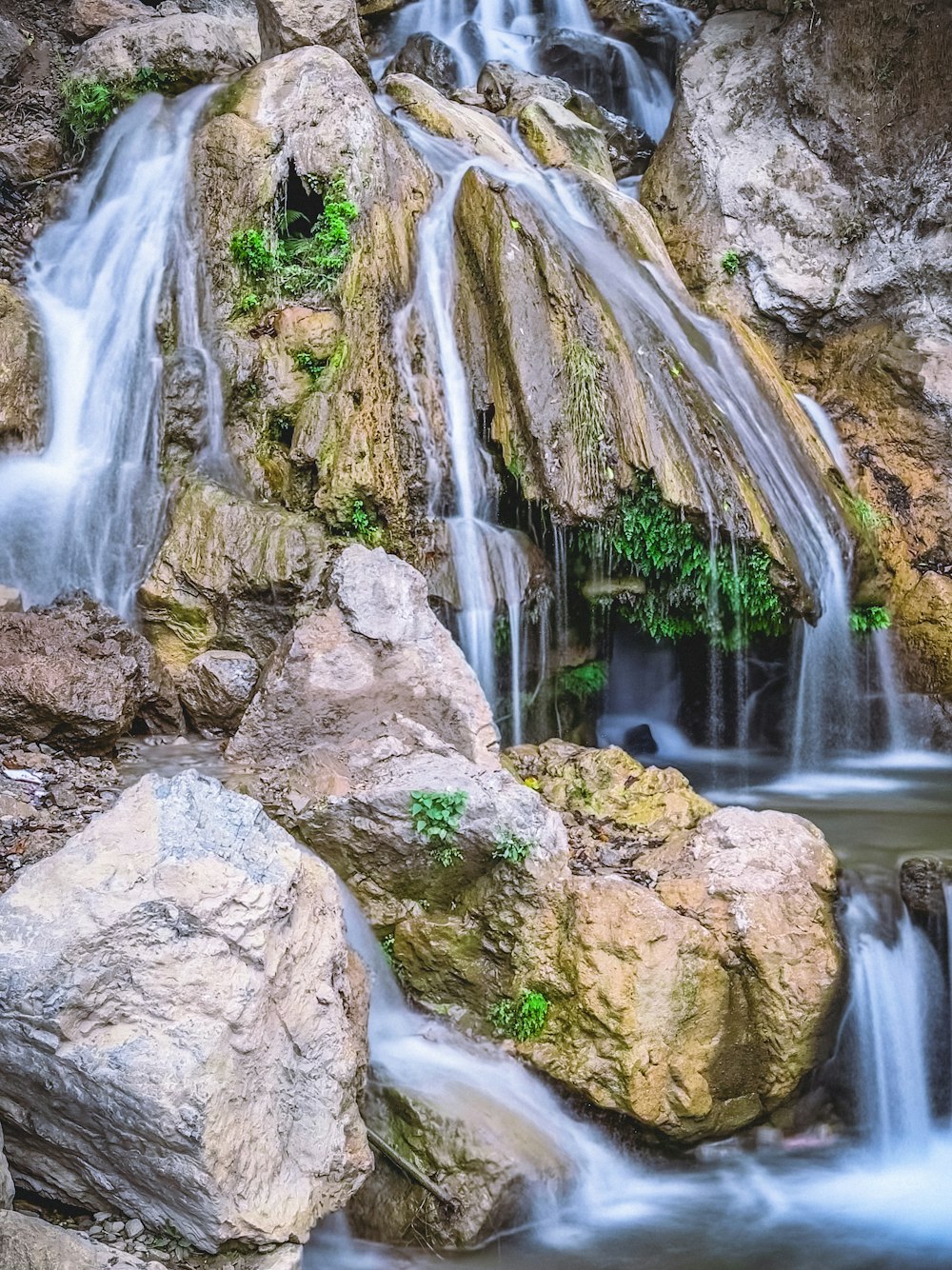 a small waterfall flowing over rocks into a pool of water