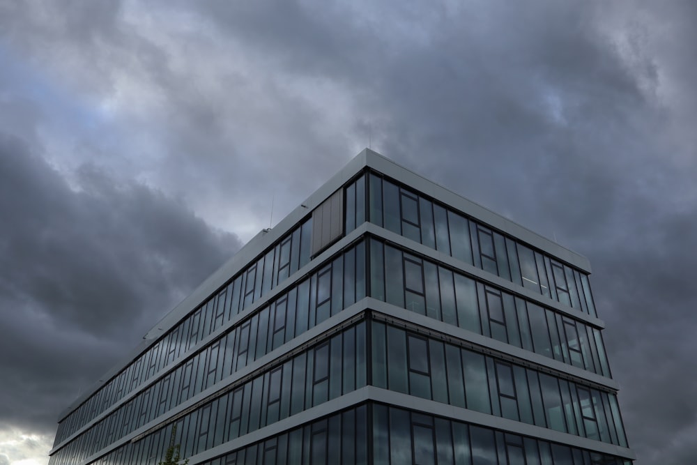 a tall glass building under a cloudy sky