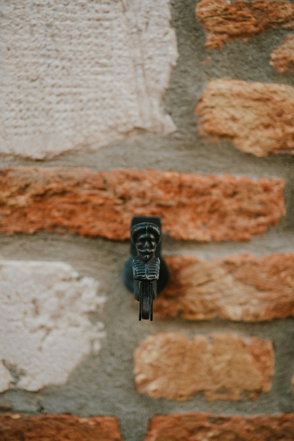 a small black statue on a brick wall