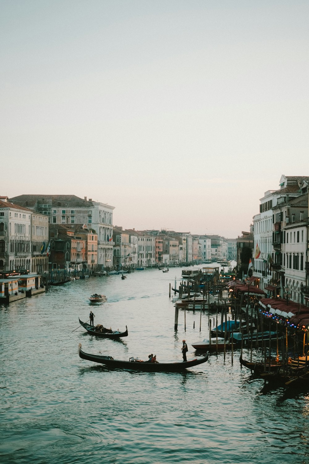 a couple of boats floating down a river next to tall buildings