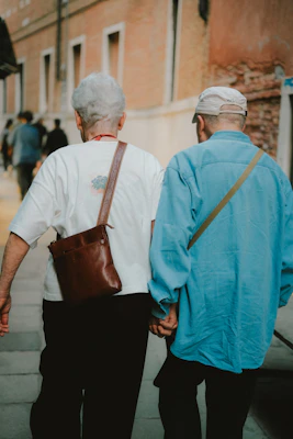 Two older friends walking together outdoors, holding hands