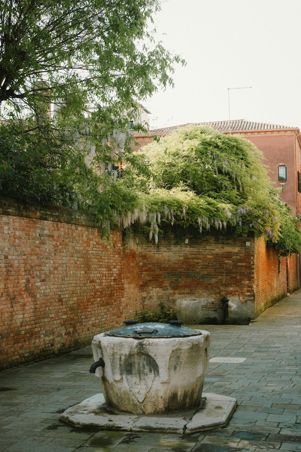 a stone fountain in a courtyard next to a brick wall