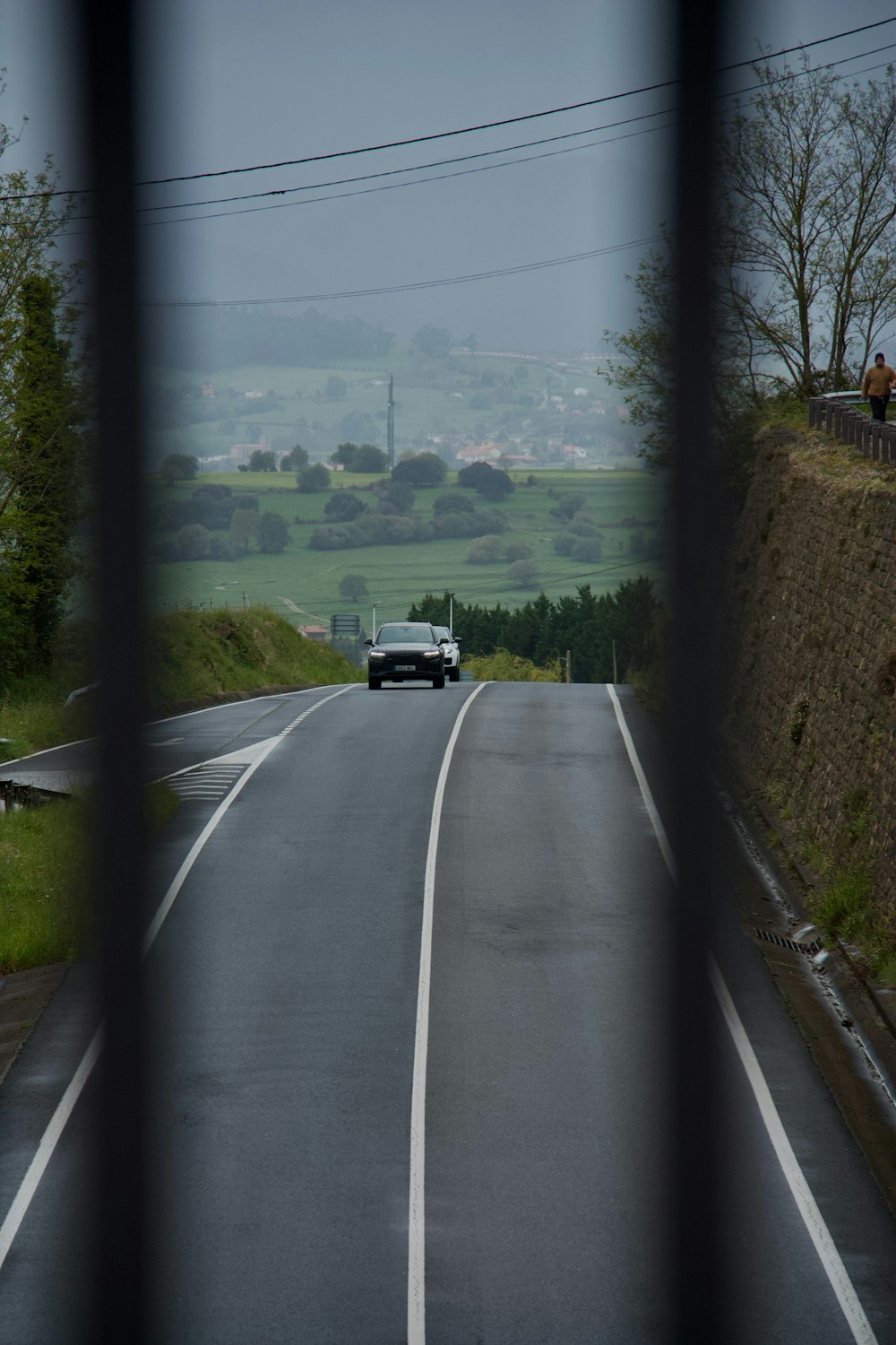 a car driving down a road next to a lush green hillside