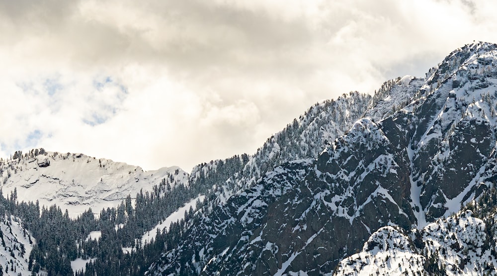 a mountain covered in snow under a cloudy sky