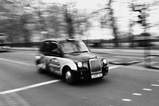 a black and white photo of a car driving down a street