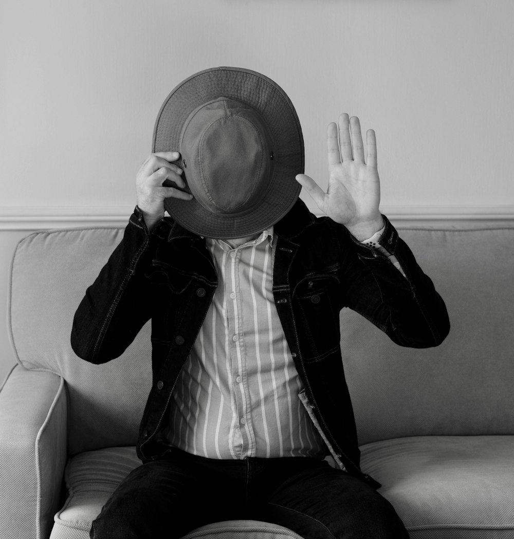 a man sitting on a couch wearing a hat