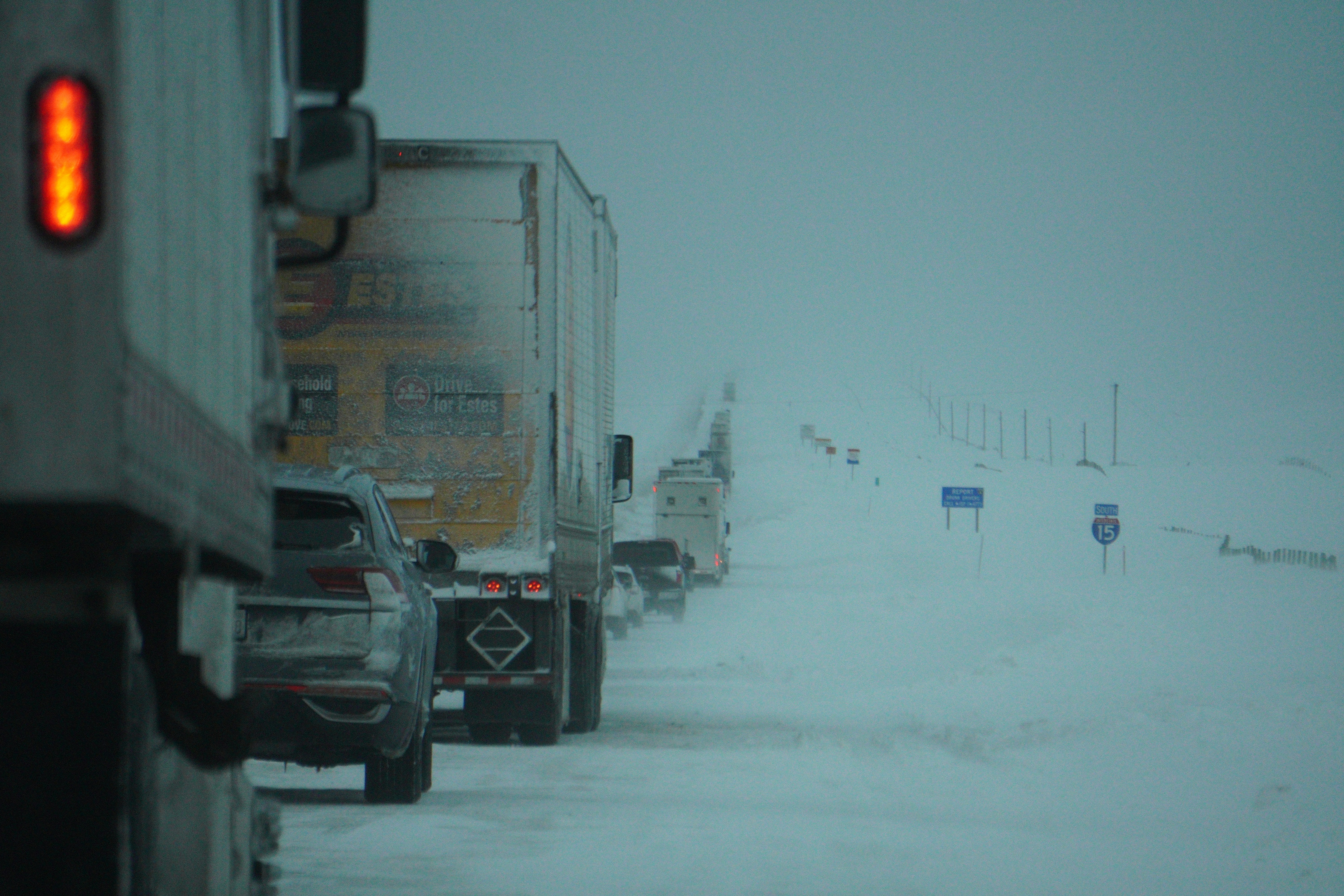 a couple of trucks driving down a snow covered road