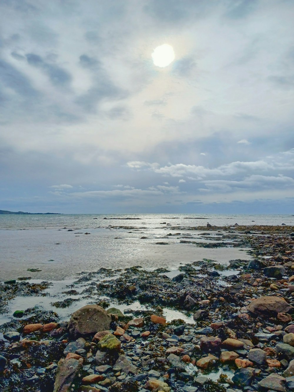 una playa con rocas y agua bajo un cielo nublado