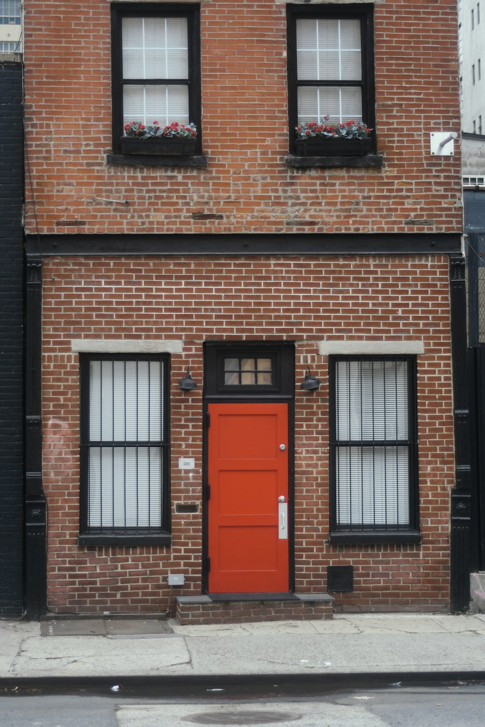 ein Backsteingebäude mit roter Tür und Fenstern