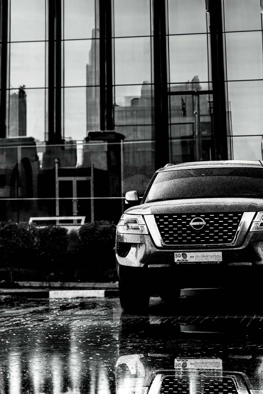 a black and white photo of a car parked in front of a building