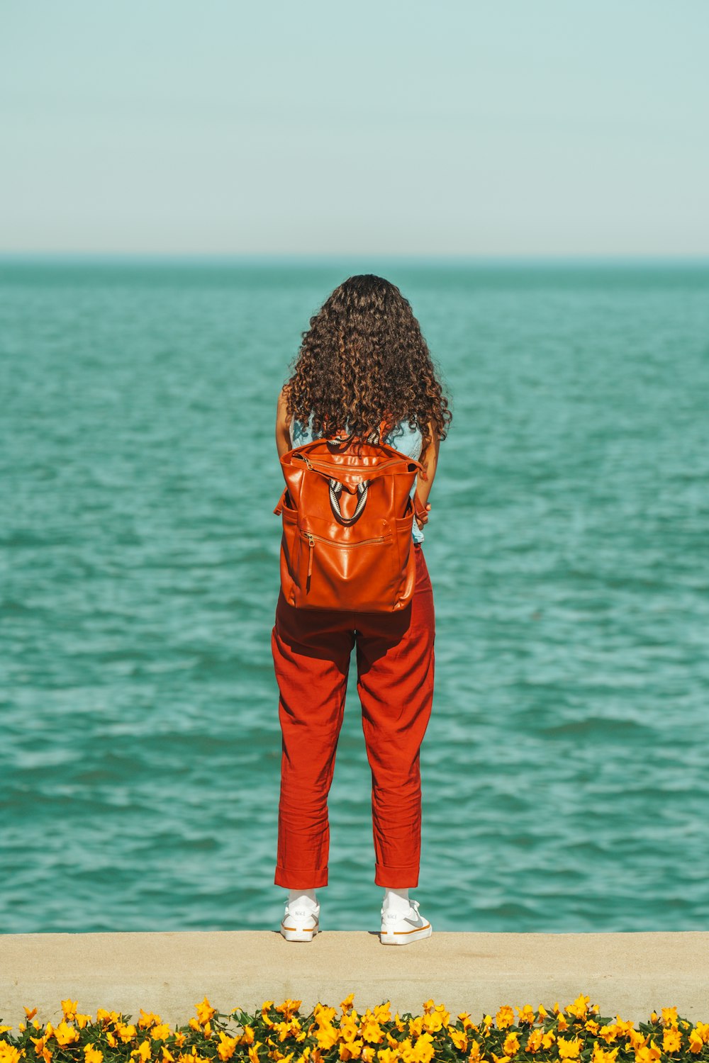 a woman standing on the edge of a pier looking at the water