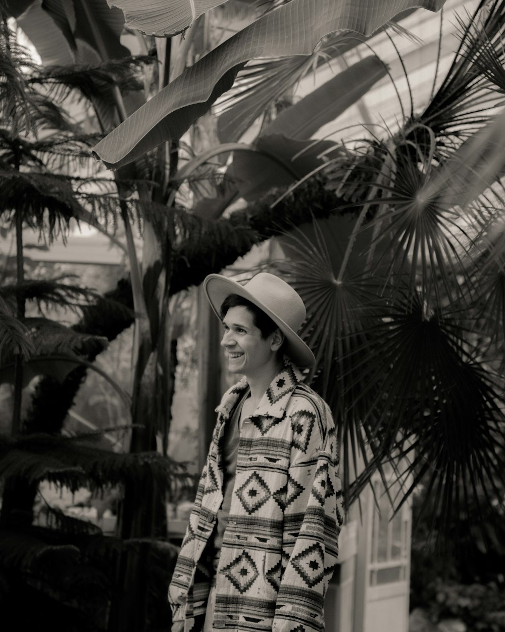 a man in a hat is standing in front of a palm tree
