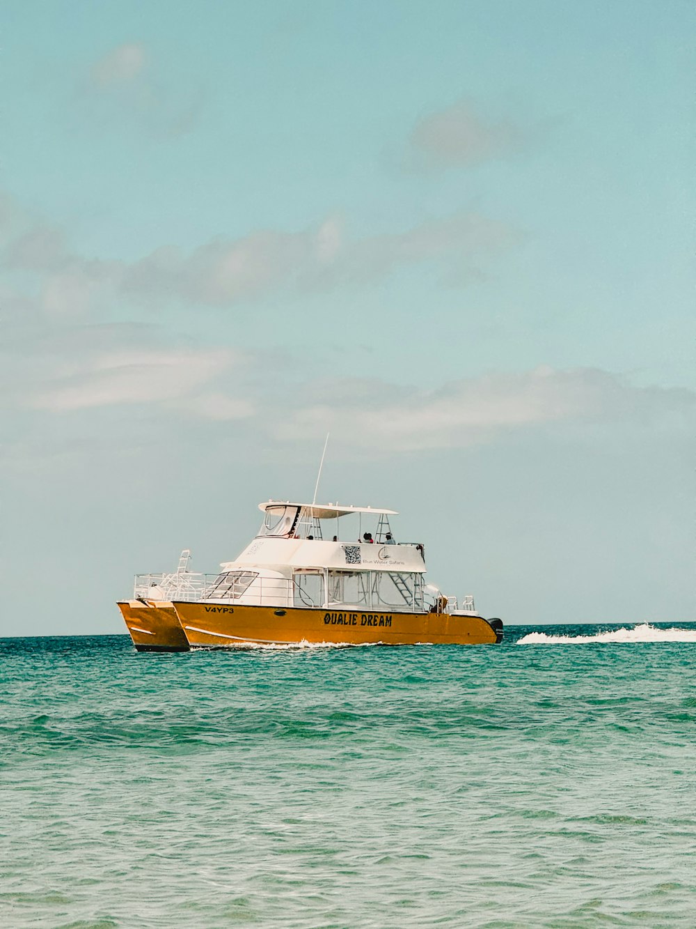 a yellow and white boat in the middle of the ocean