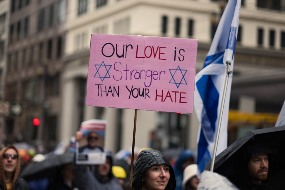 a woman holding a sign that says our love is faster than your hate