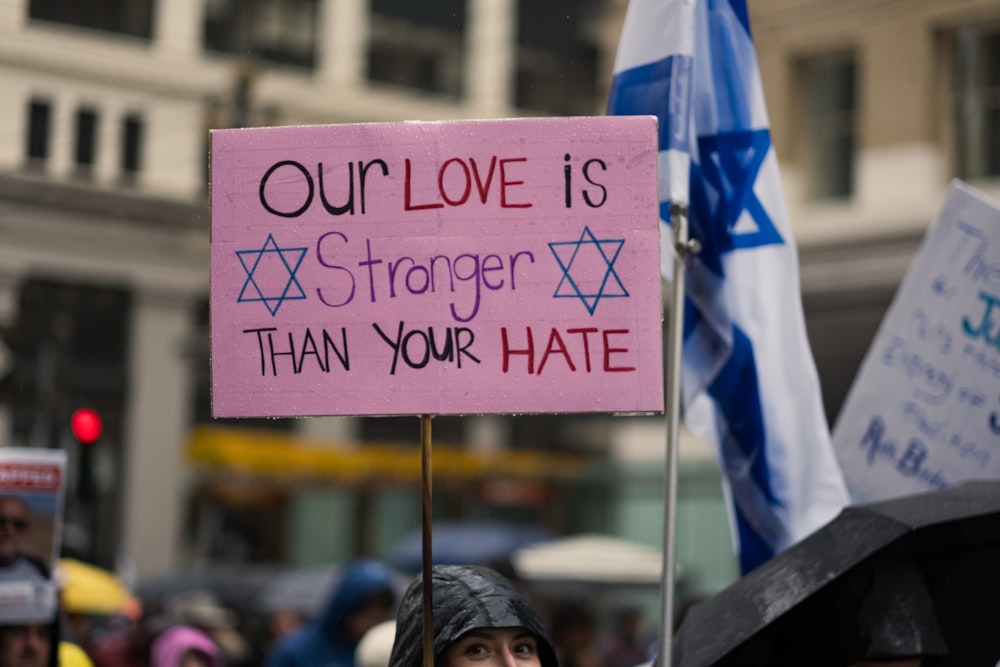 a person holding a sign that says our love is stronger than your hate