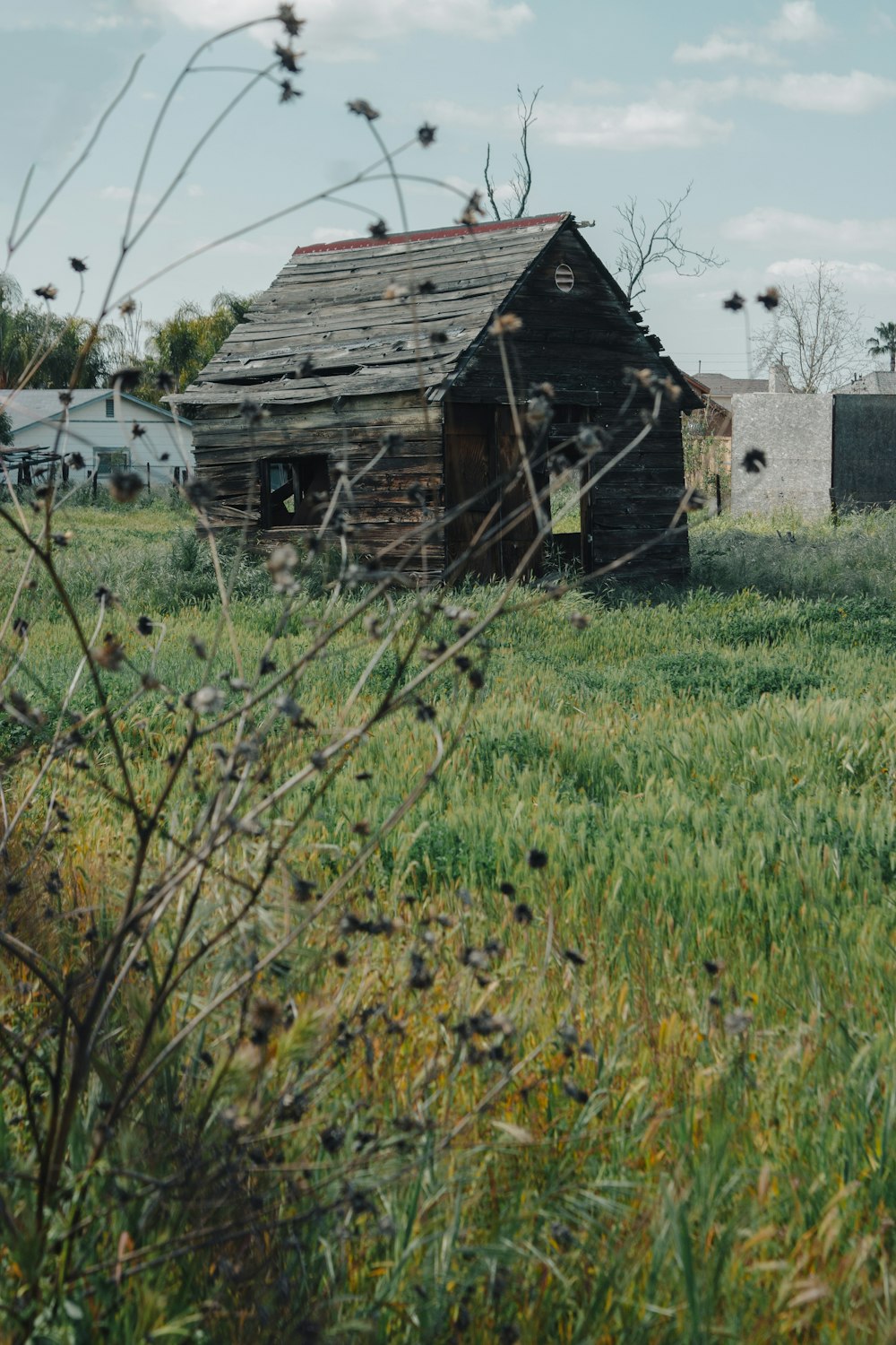 an old wooden shack in a grassy field