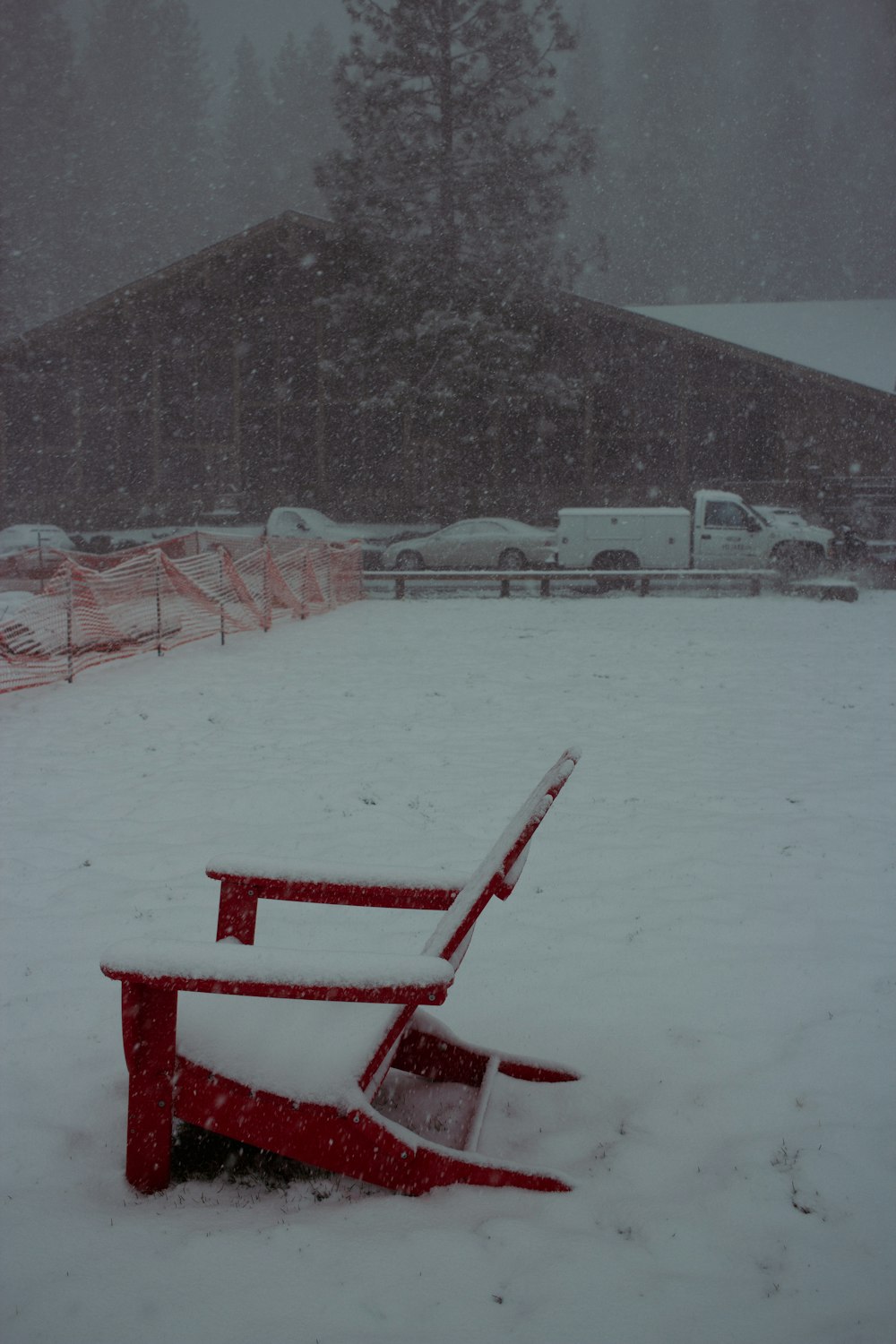 um banco vermelho sentado no meio de um campo coberto de neve