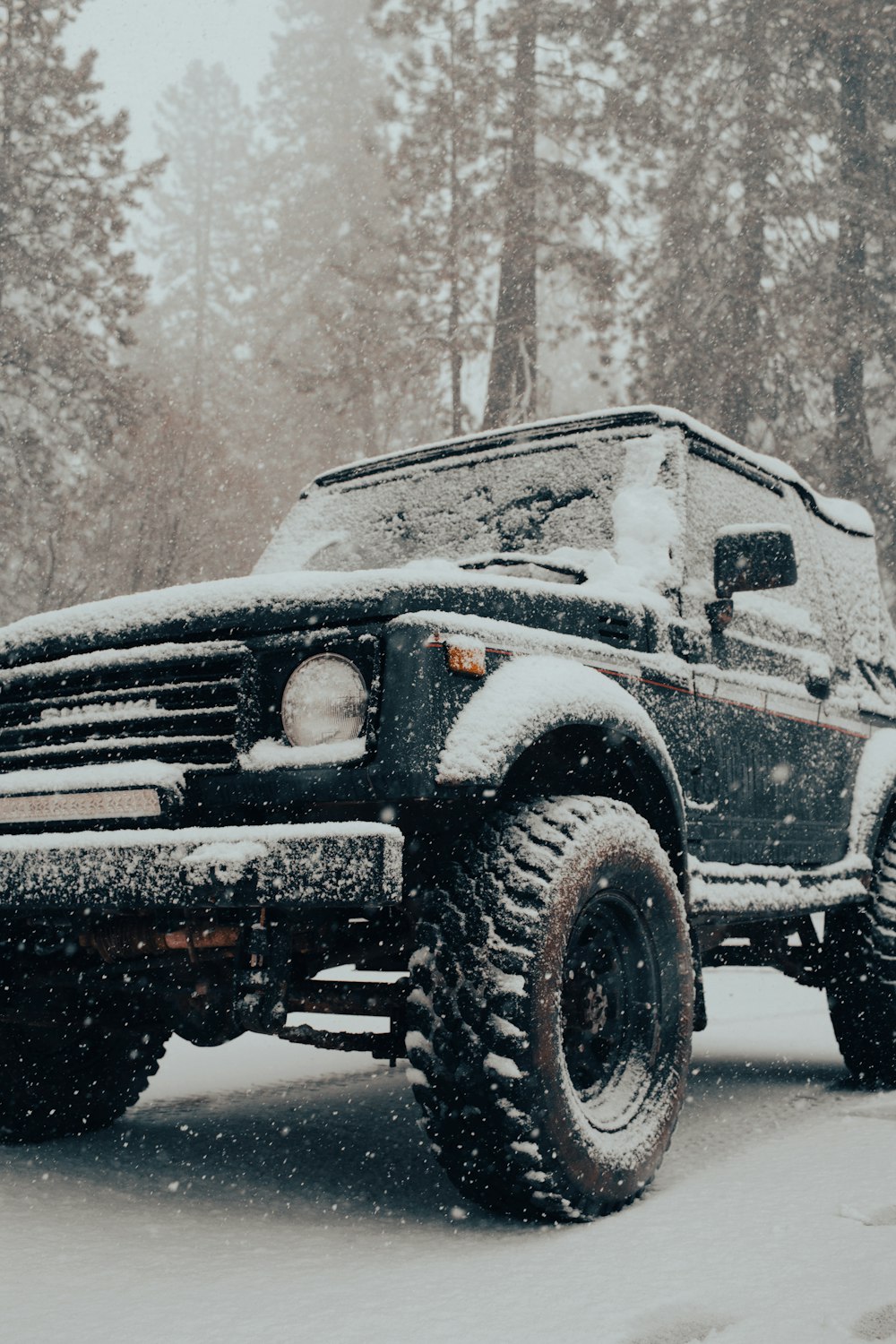 a black truck driving down a snow covered road