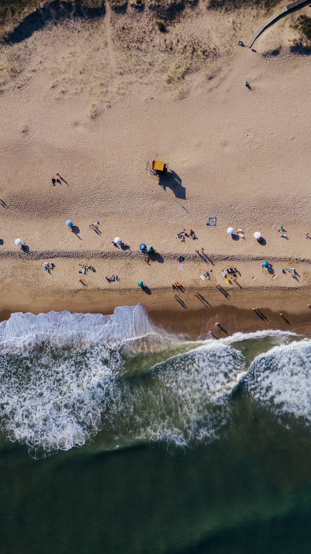 Eine Luftaufnahme eines Strandes mit Menschen und Sonnenschirmen