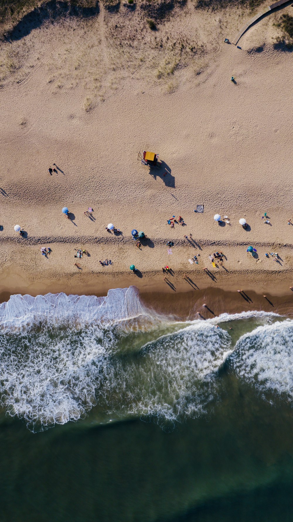 an aerial view of a beach with people and umbrellas