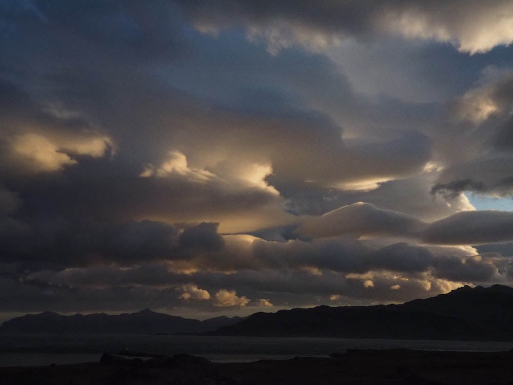 a cloudy sky with mountains in the distance