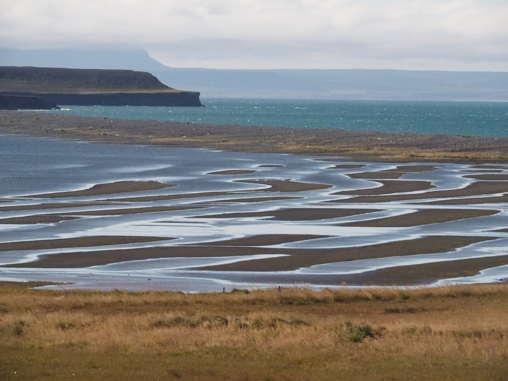 a large body of water sitting next to a lush green field