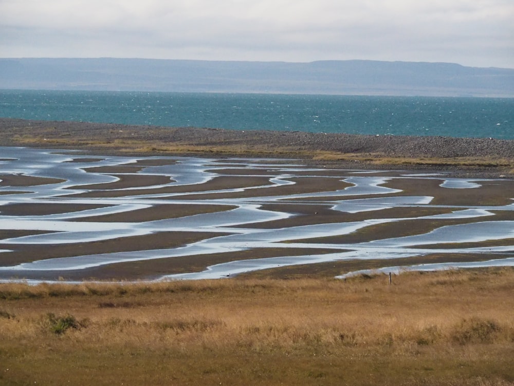 a large body of water sitting on top of a dry grass field