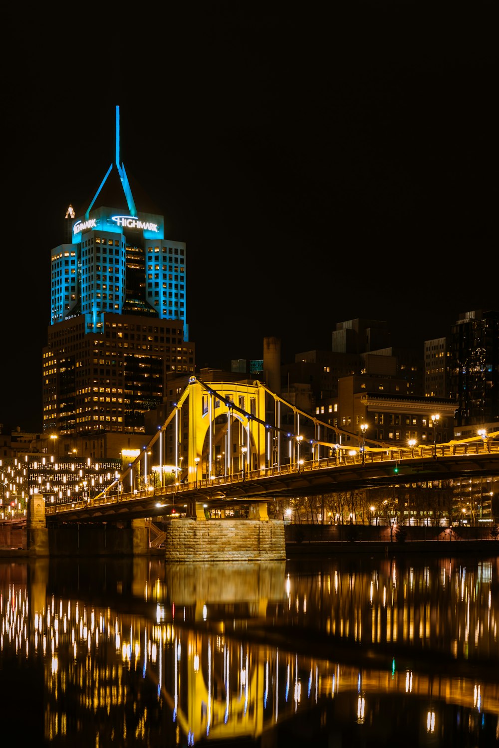 a city skyline at night with a bridge over a body of water