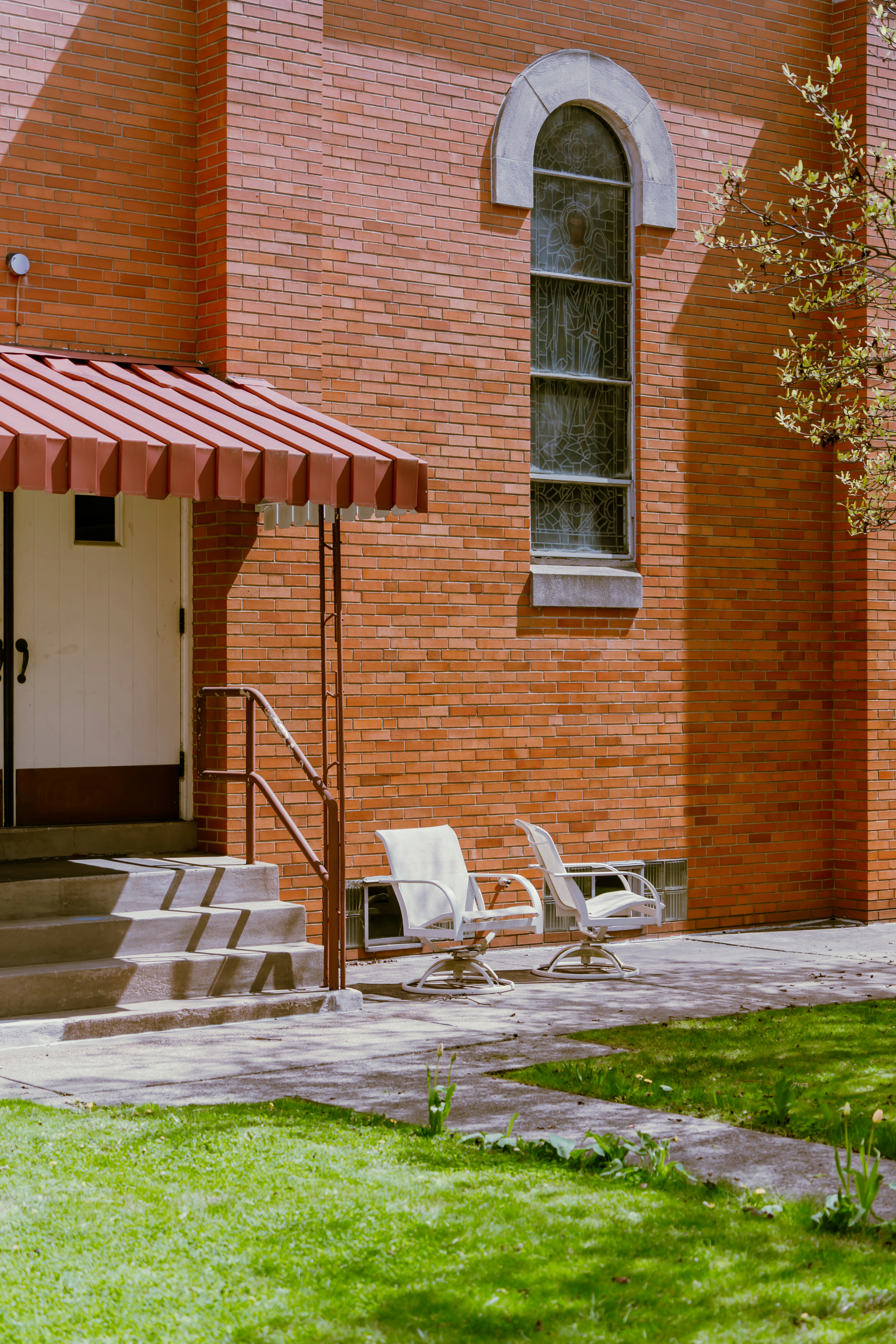 a brick building with a red awning and lawn chairs
