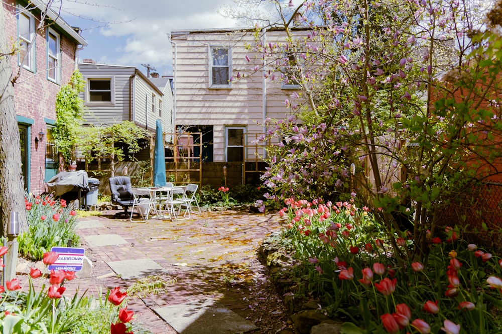 a garden with flowers and a house in the background