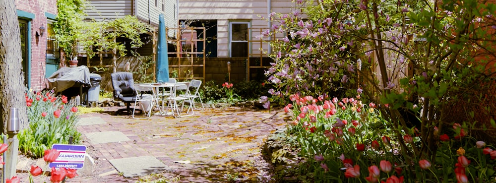 a garden with flowers and a table and chairs