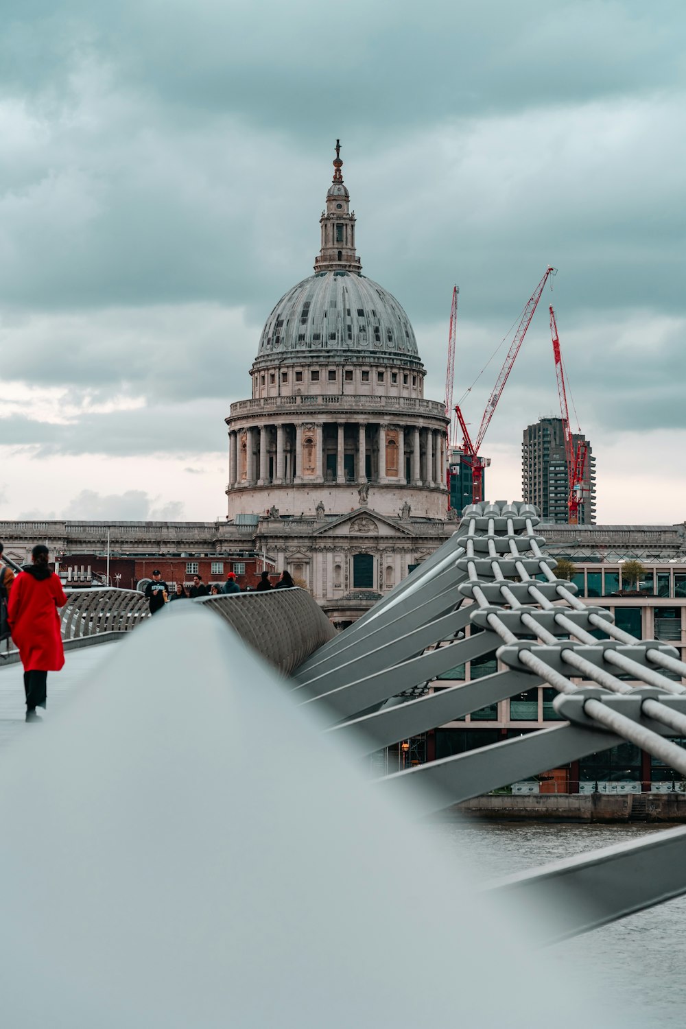 a person in a red coat walking across a bridge