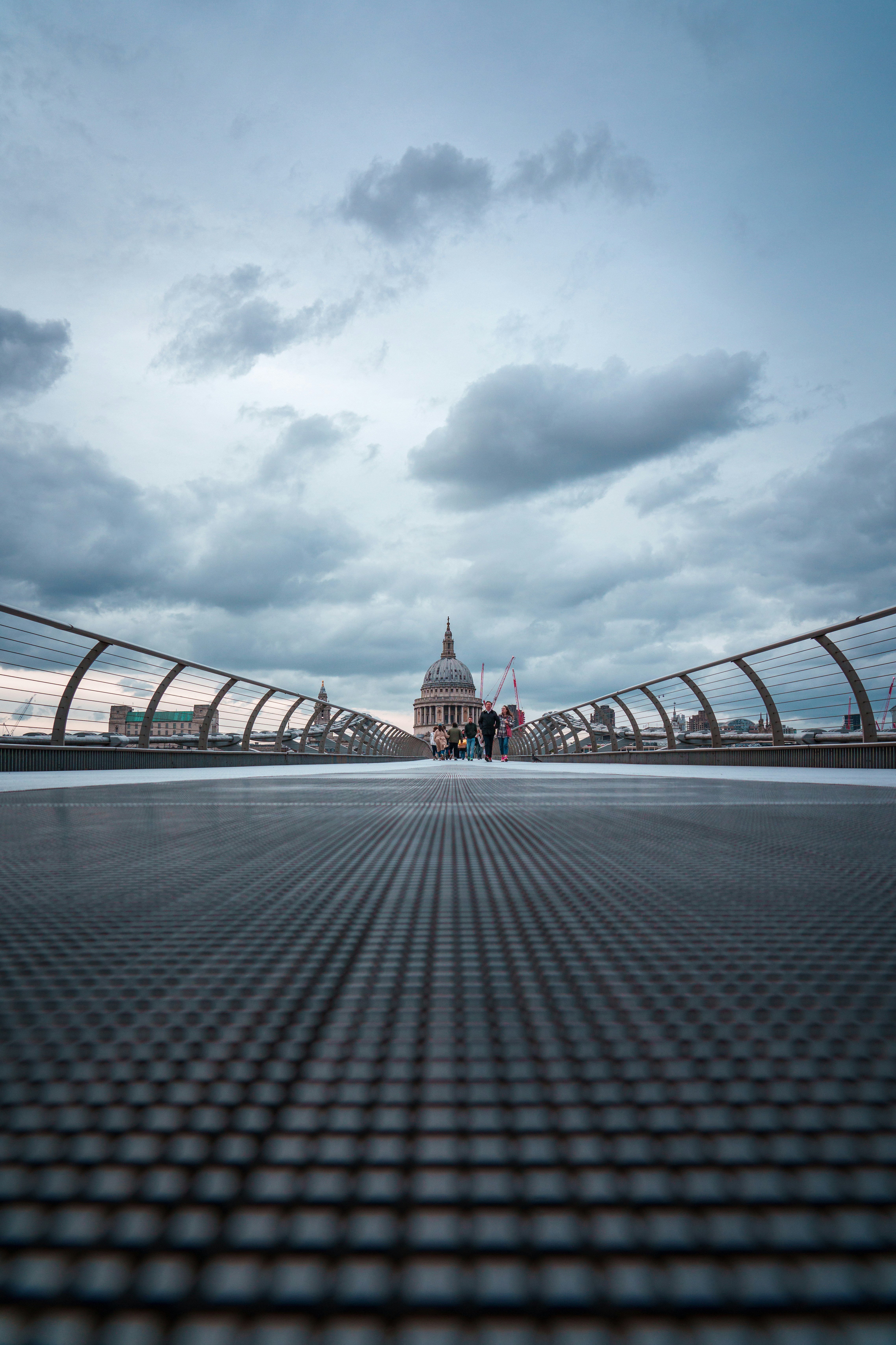 people walking across a bridge on a cloudy day