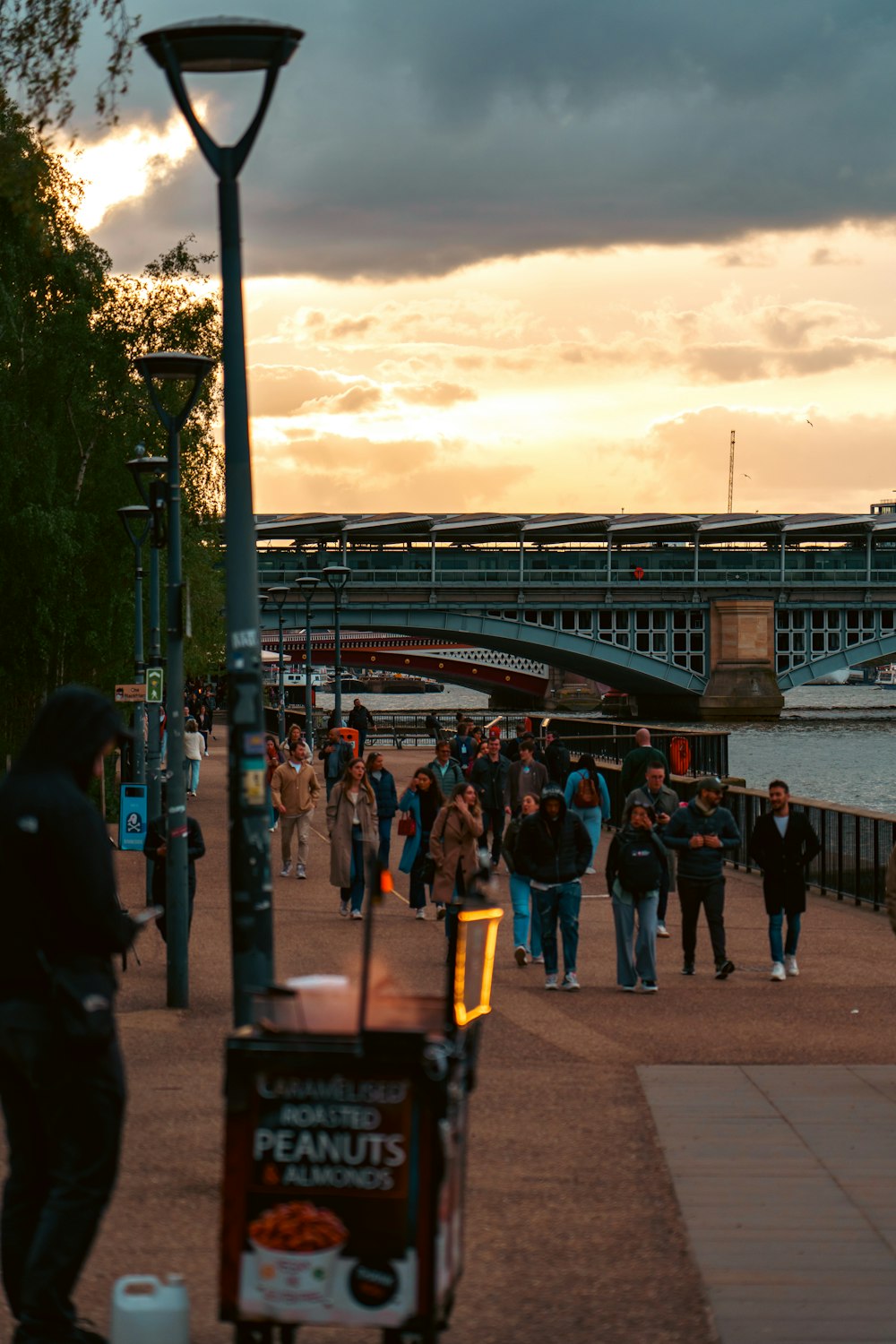 a group of people walking down a sidewalk next to a street light