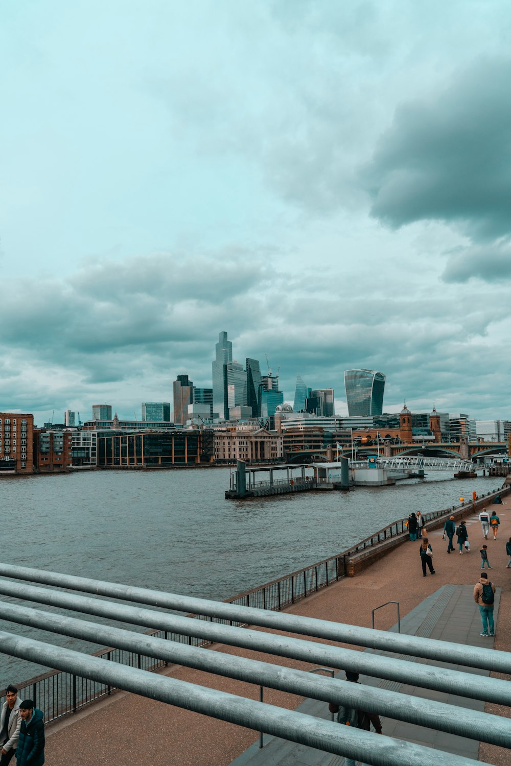 a group of people walking along a river next to a city