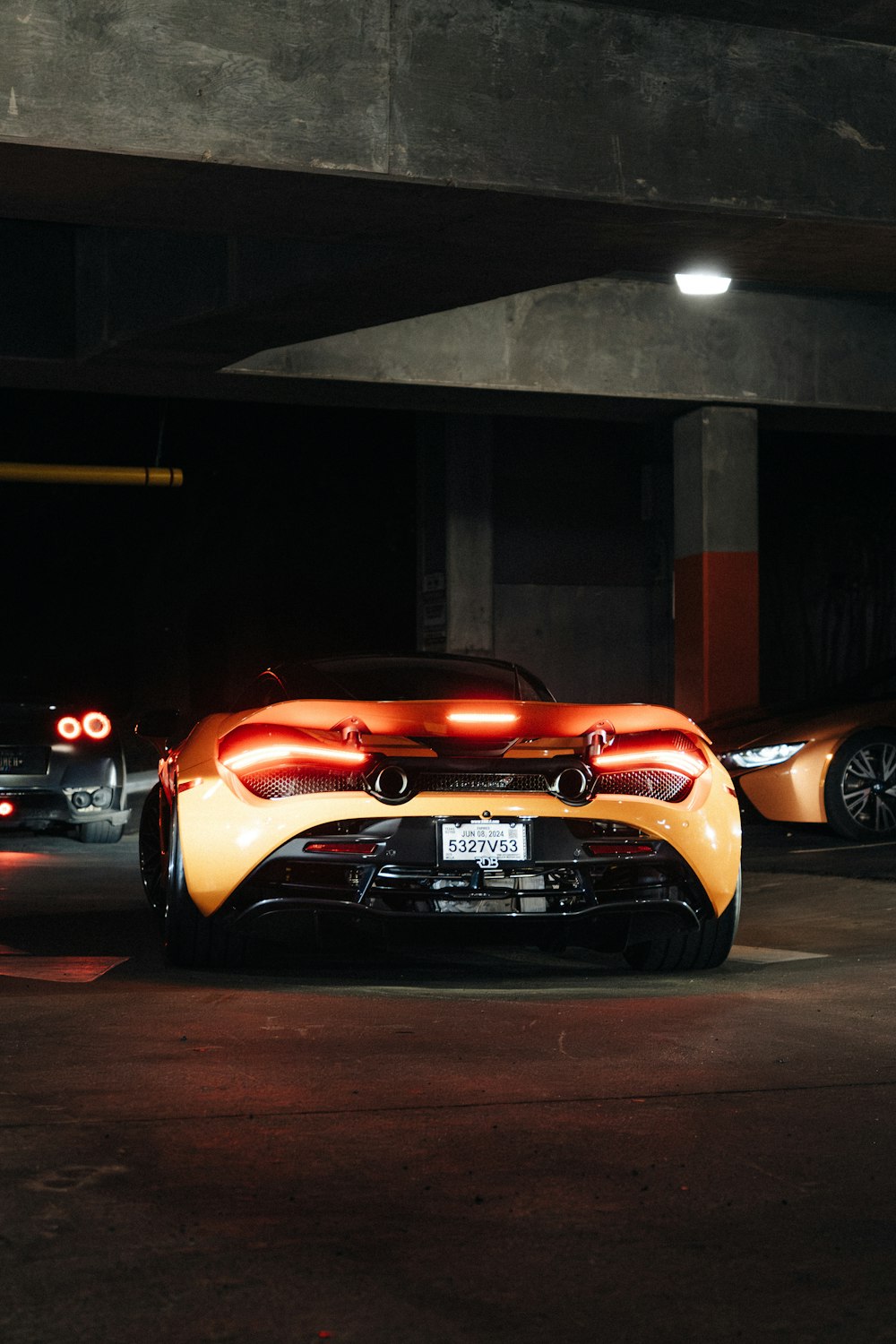 two orange sports cars parked in a parking garage