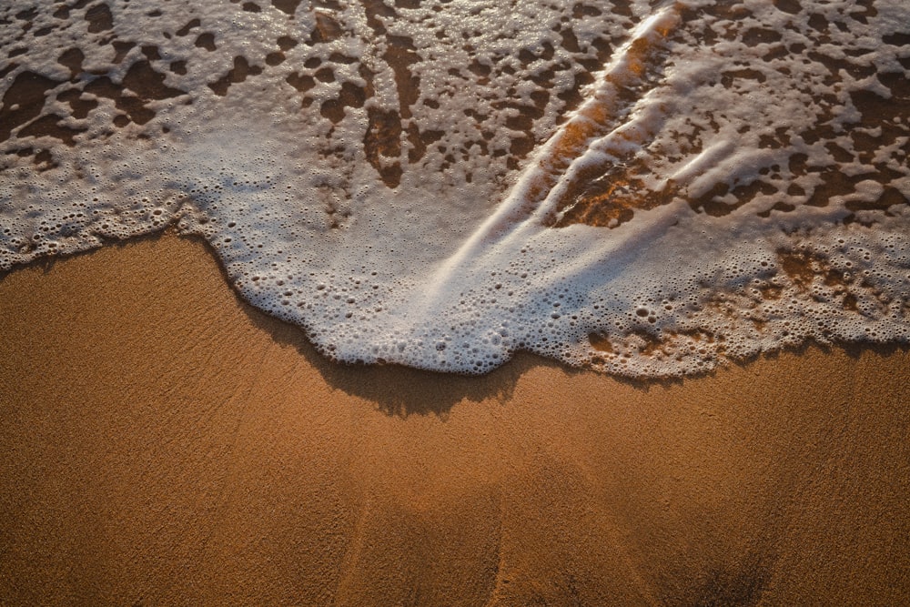 a sandy beach with a wave coming in to shore