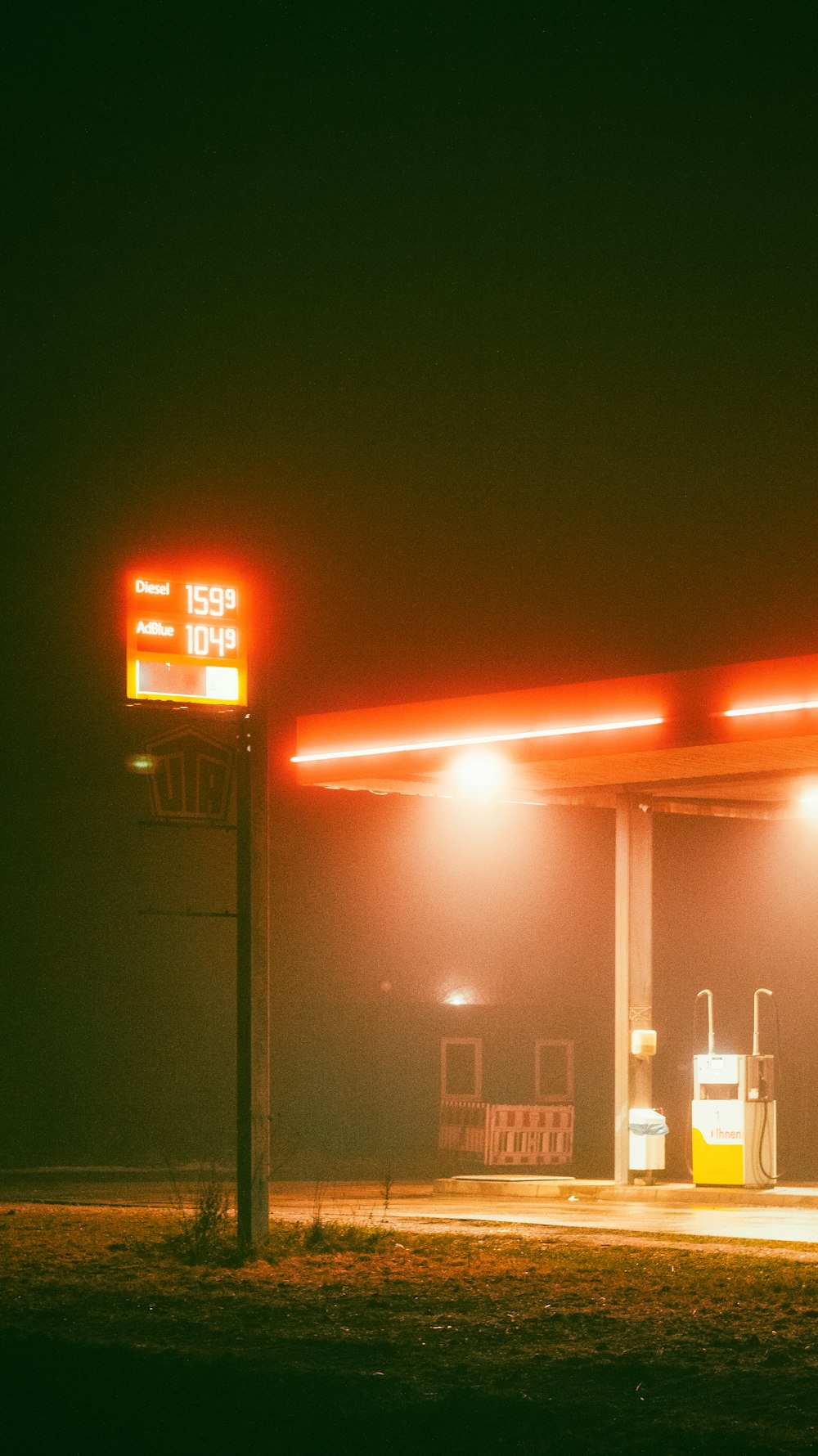 um posto de gasolina à noite com um sinal vermelho