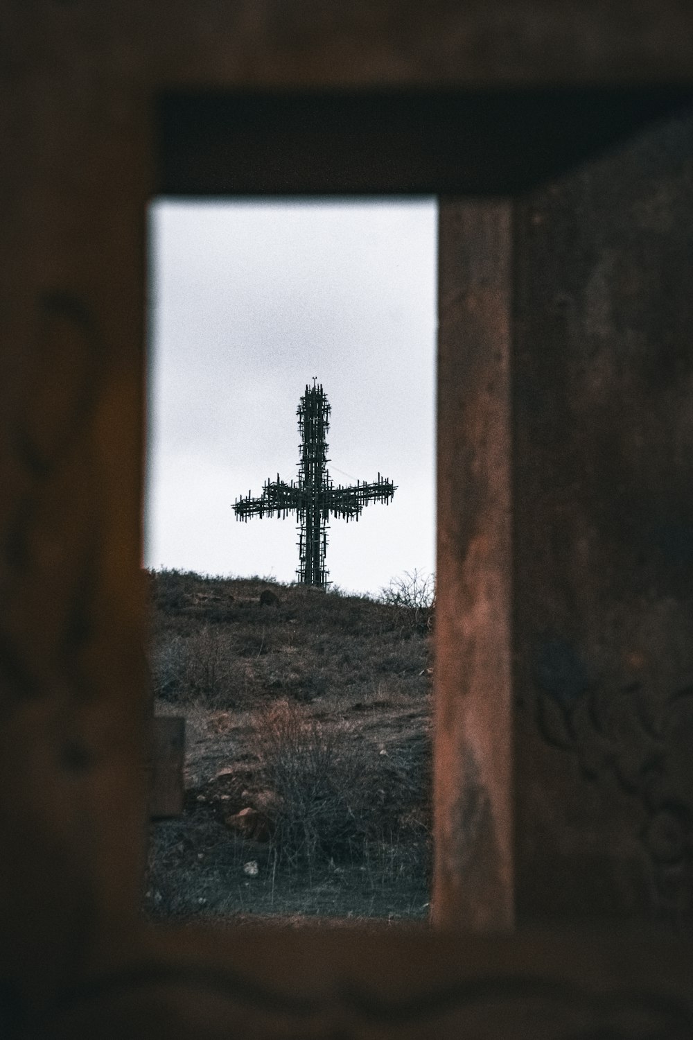 a cross is seen through a hole in a wall
