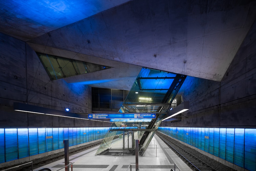 an empty subway station with blue lights on the ceiling