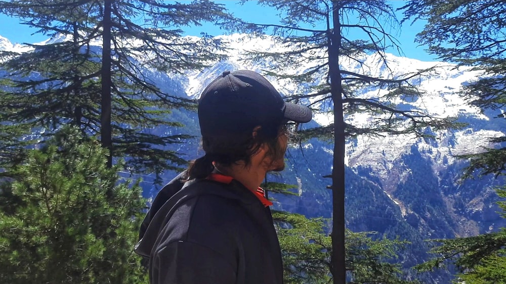 a man standing in the woods looking at the mountains