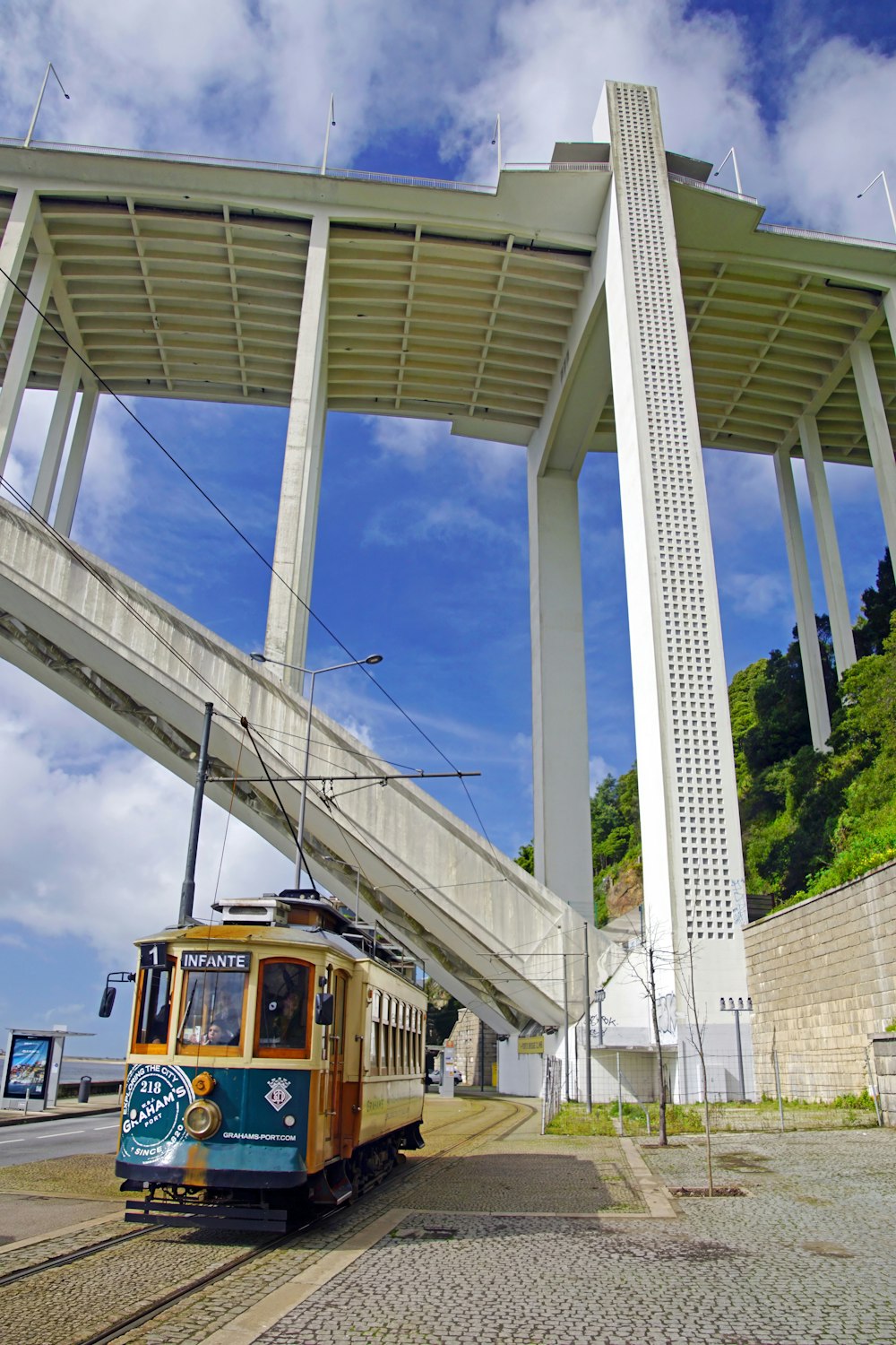 a cable car going under a bridge with a sky background