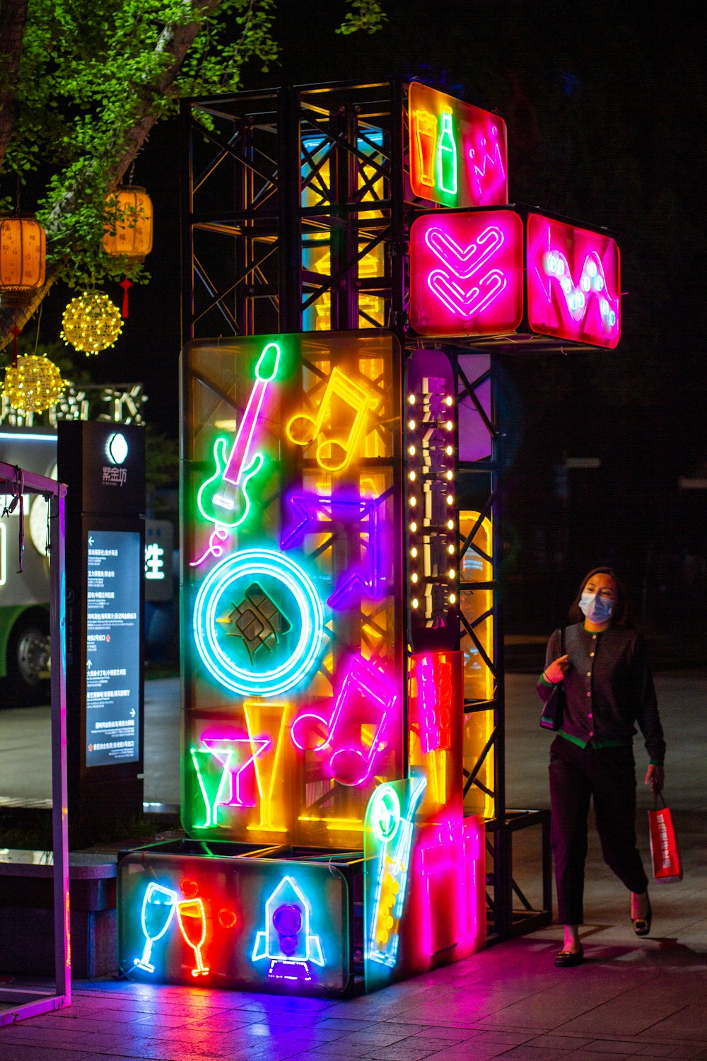 a person wearing a face mask standing in front of a display of neon signs